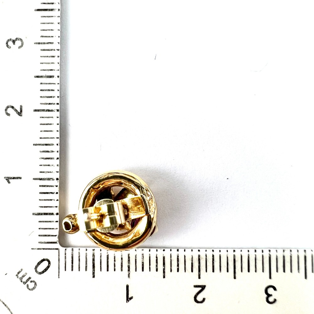 A pair of Victorian 18ct gold stud earrings featuring textured vine leaf motifs and circular red ruby accents set on round gold discs. View VIII