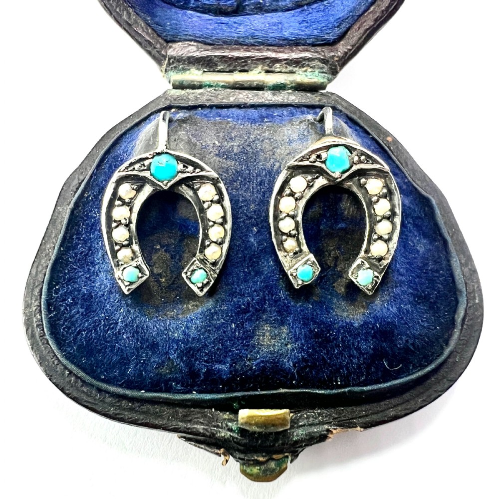 A pair of Victorian sterling silver horseshoe drop earrings set with turquoise cabochons and split seed pearls inside a velvet case.