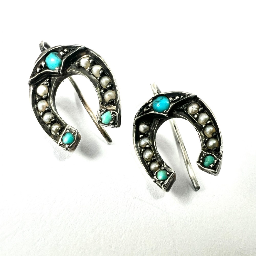 A pair of Victorian sterling silver horseshoe drop earrings set with turquoise cabochons and split seed pearls inside a velvet case. View III