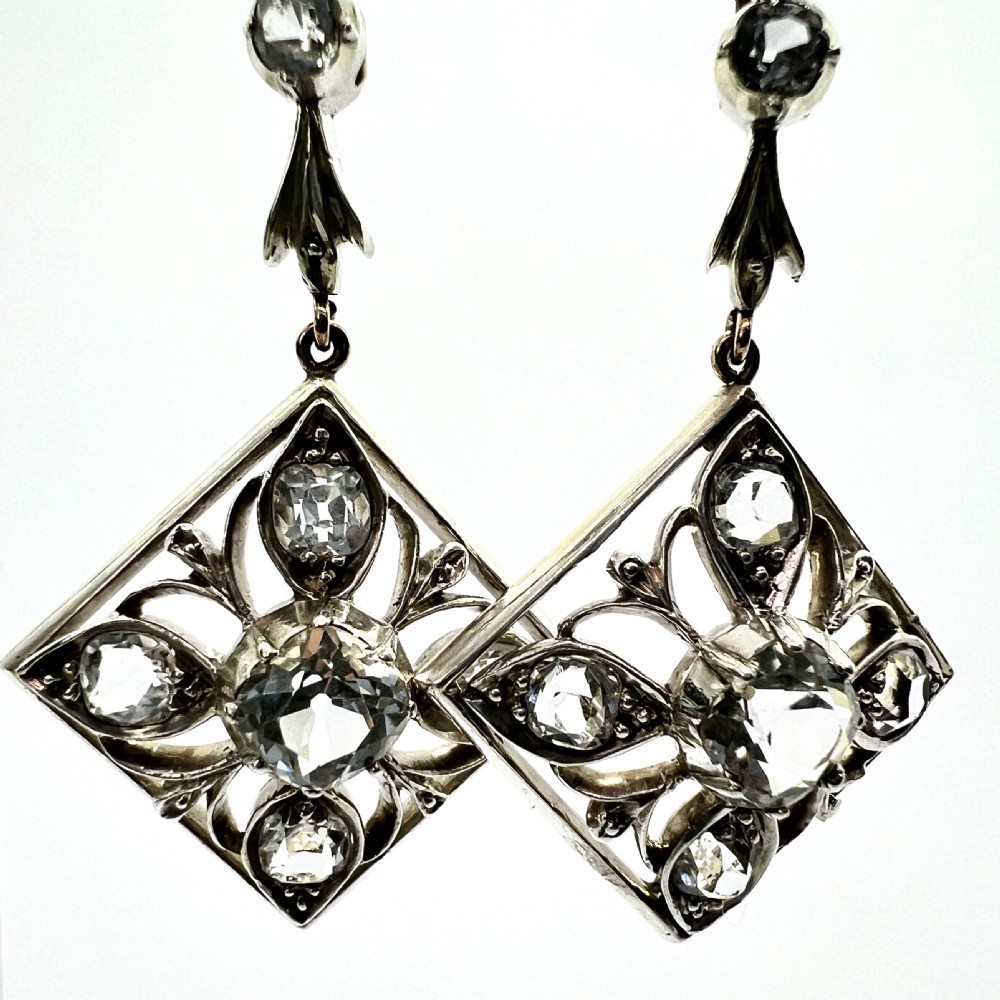 A pair of Victorian silver and 9ct gold drop earrings featuring diamond-shaped filigree openwork set with clear faceted rock crystals. View VII