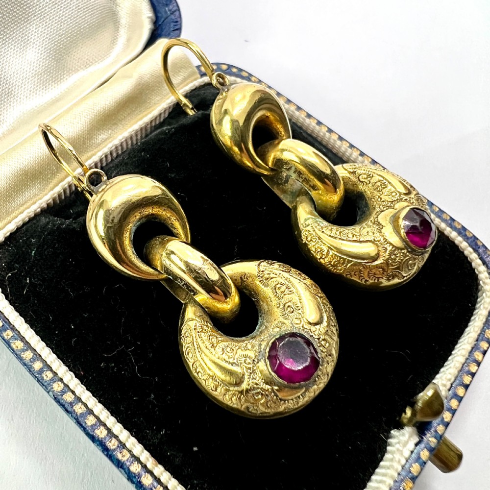 A pair of Victorian gold drop earrings featuring engraved hoop-shaped dangles inset with deep red garnet paste stones. View III