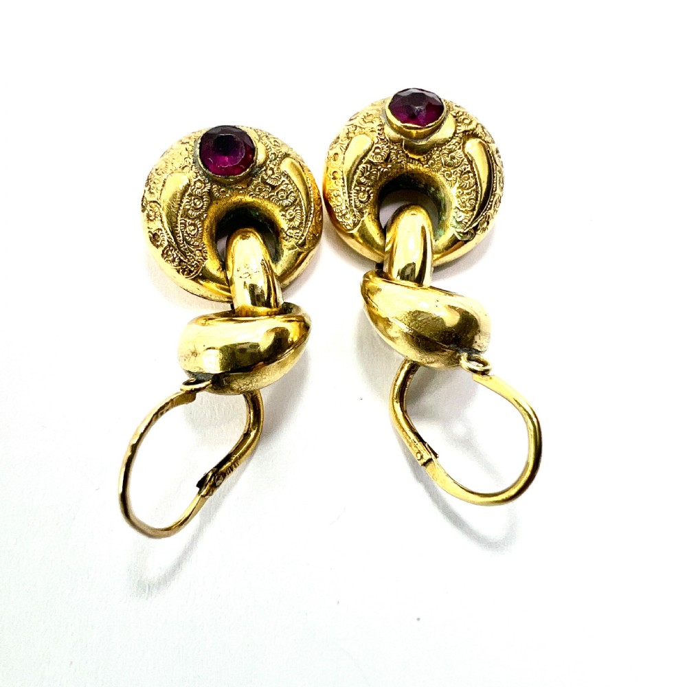 A pair of Victorian gold drop earrings featuring engraved hoop-shaped dangles inset with deep red garnet paste stones. View VII