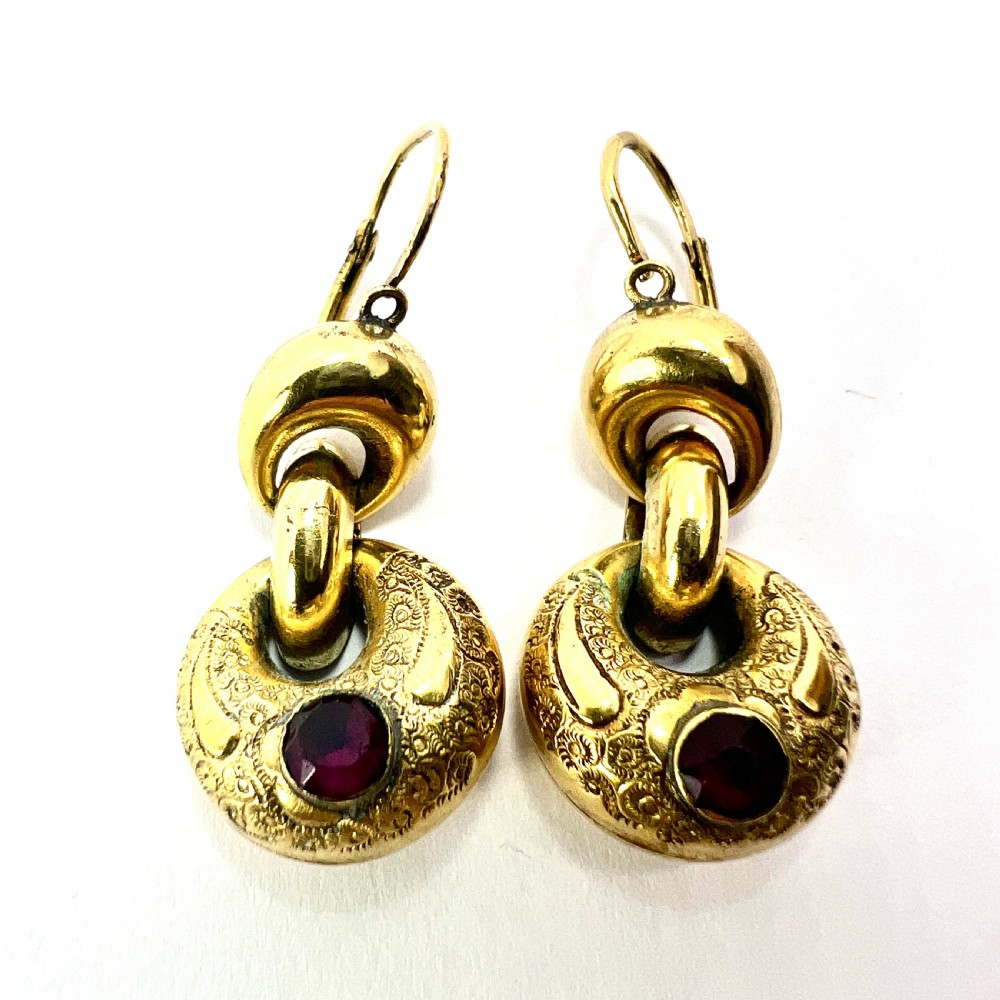 A pair of Victorian gold drop earrings featuring engraved hoop-shaped dangles inset with deep red garnet paste stones. View VIII