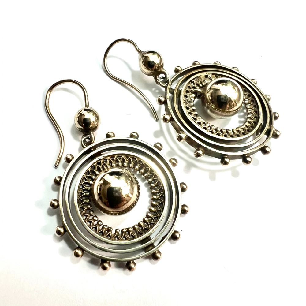 A pair of Victorian silver gilt drop earrings featuring concentric circular tiers around a polished central dome with beaded decorative accents. View II