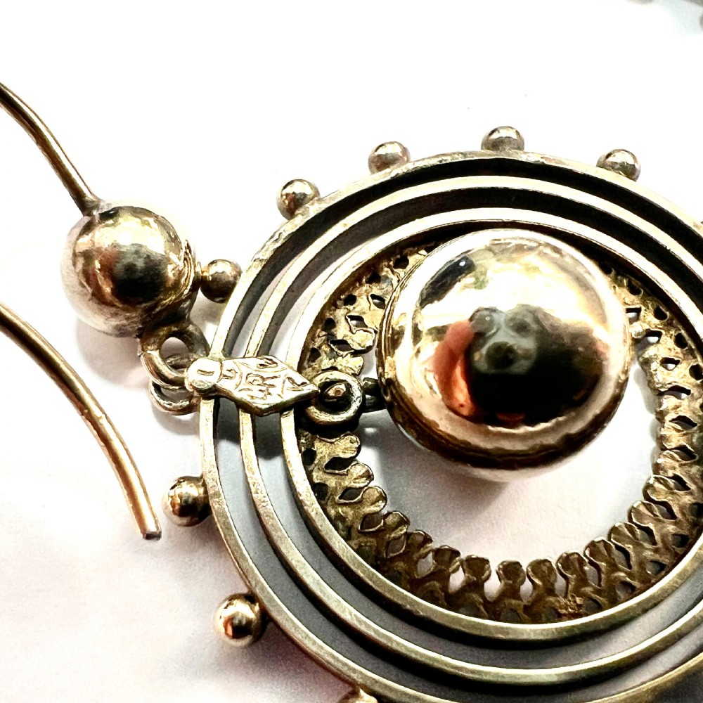A pair of Victorian silver gilt drop earrings featuring concentric circular tiers around a polished central dome with beaded decorative accents. View V