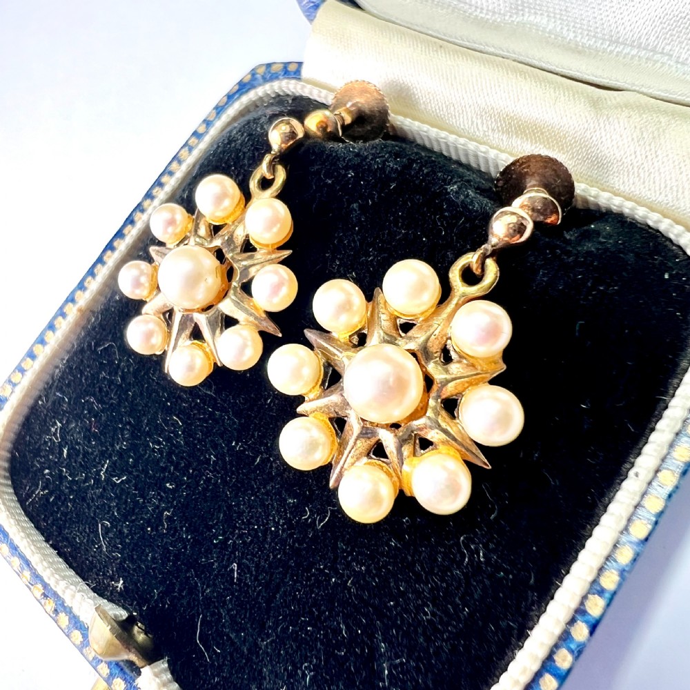 A pair of vintage 9ct gold screwback earrings featuring a central pearl surrounded by a sunburst frame set with smaller pearls. View II