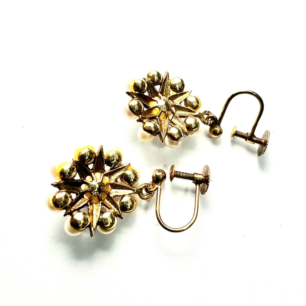 A pair of vintage 9ct gold screwback earrings featuring a central pearl surrounded by a sunburst frame set with smaller pearls. View IV