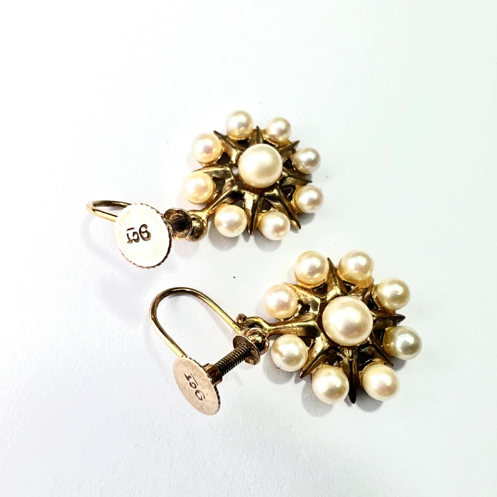 A pair of vintage 9ct gold screwback earrings featuring a central pearl surrounded by a sunburst frame set with smaller pearls. View V