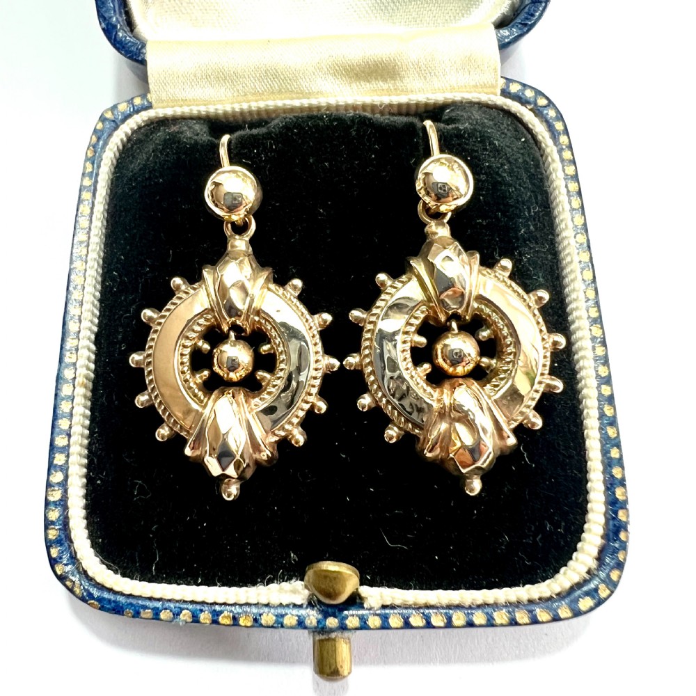 A pair of Victorian 9ct yellow gold drop earrings featuring circular wheel-like motifs with central spherical beads suspended from wire hooks.