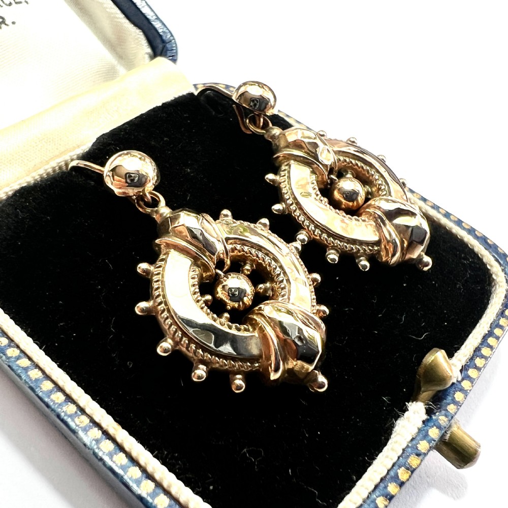 A pair of Victorian 9ct yellow gold drop earrings featuring circular wheel-like motifs with central spherical beads suspended from wire hooks. View II