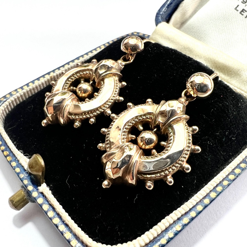 A pair of Victorian 9ct yellow gold drop earrings featuring circular wheel-like motifs with central spherical beads suspended from wire hooks. View III