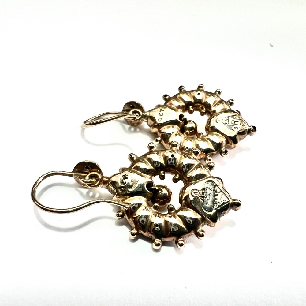 A pair of Victorian 9ct yellow gold drop earrings featuring circular wheel-like motifs with central spherical beads suspended from wire hooks. View V