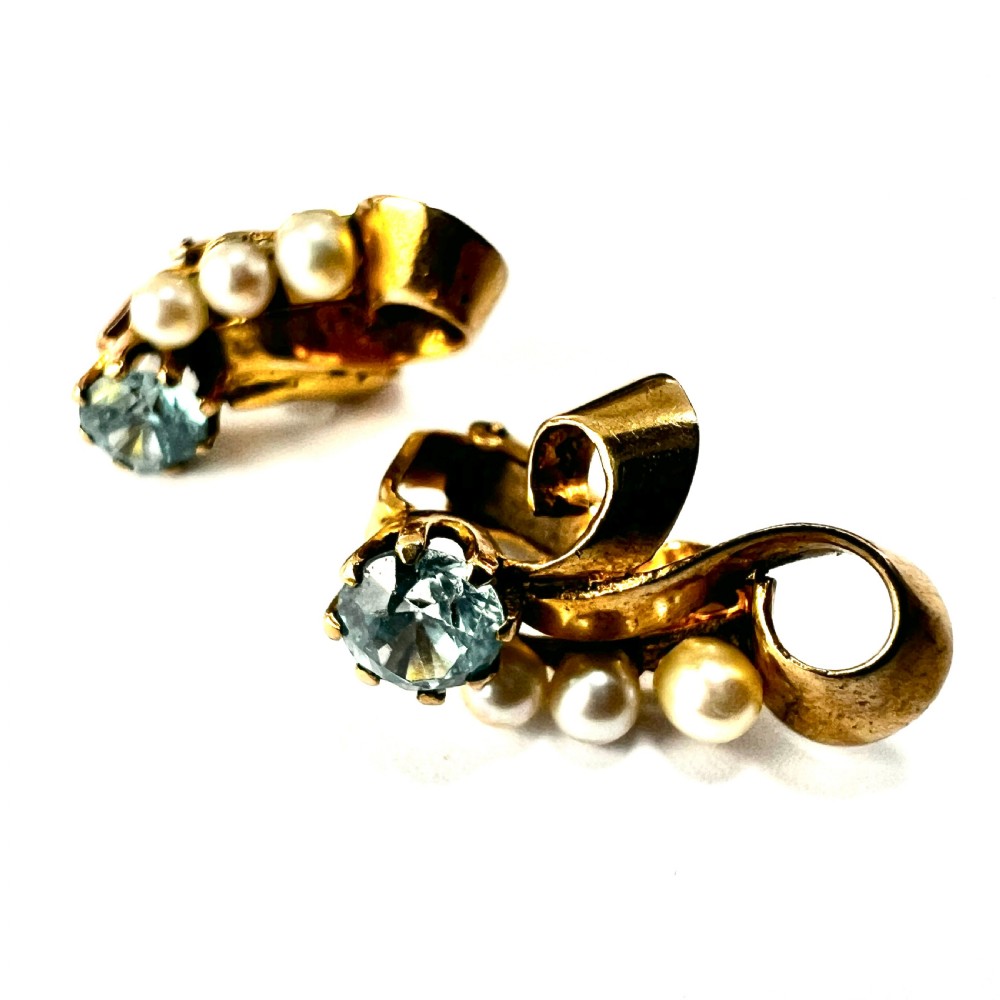 A pair of 1940s 9ct yellow gold ear clips featuring faceted round blue zircons and graduated pearls set against curved ribbon scrollwork. View III