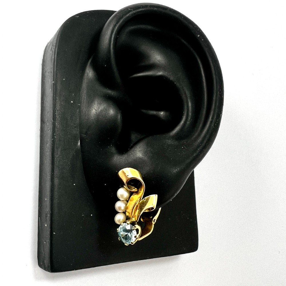 A pair of 1940s 9ct yellow gold ear clips featuring faceted round blue zircons and graduated pearls set against curved ribbon scrollwork. View IX