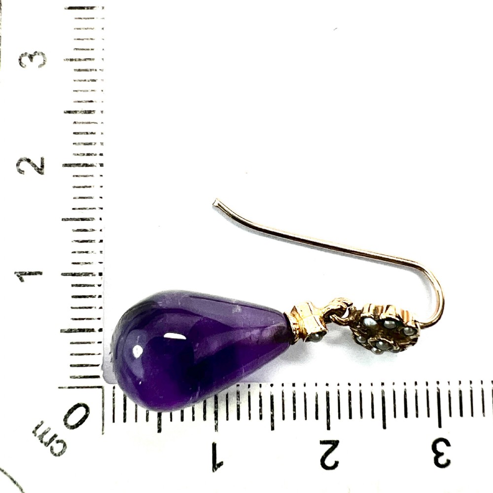 A pair of Victorian gold drop earrings featuring teardrop cabochon amethysts suspended from pearl-set floral clusters inside a fitted velvet box. View VII