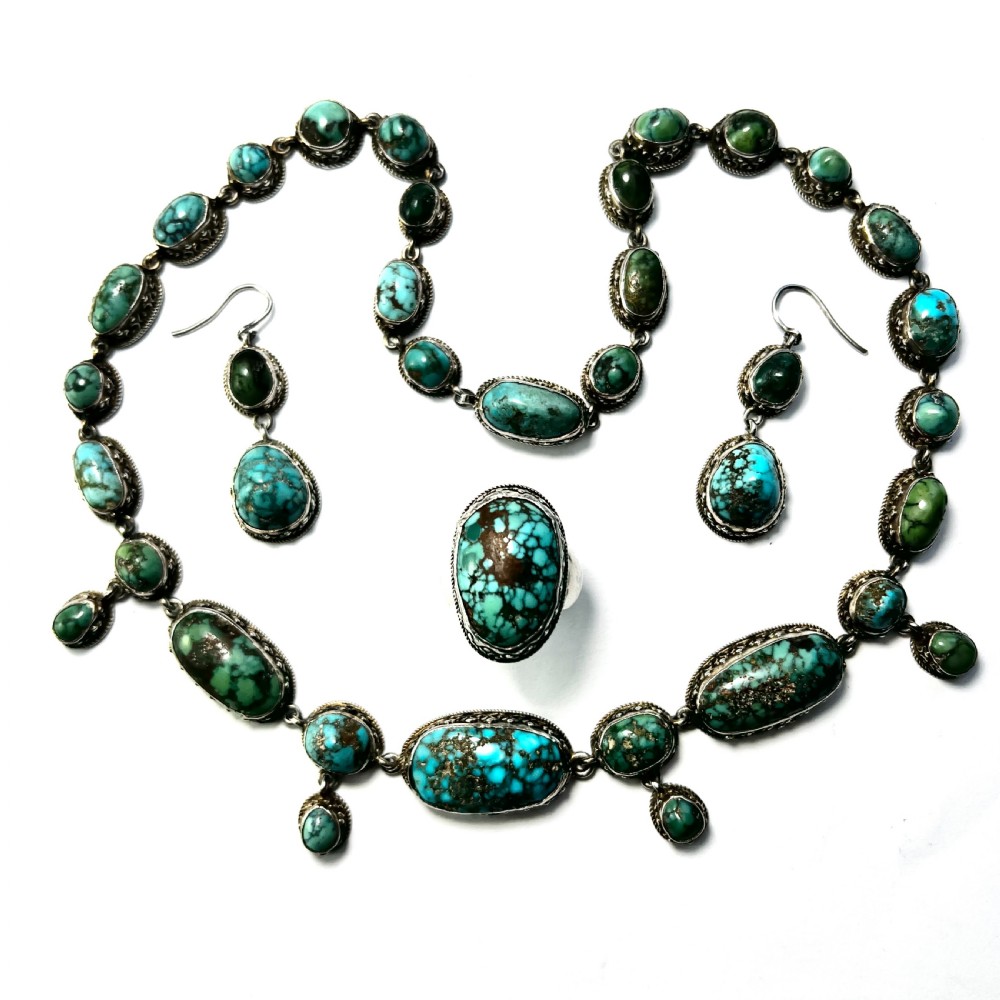 An antique silver jewellery parure consisting of a cabochon turquoise matrix link necklace, drop earrings, and a statement ring.