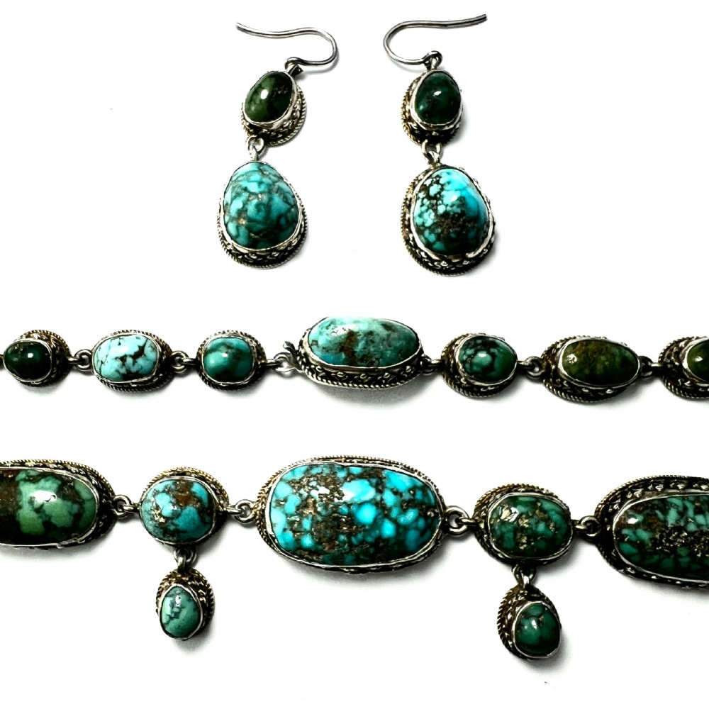 An antique silver jewellery parure consisting of a cabochon turquoise matrix link necklace, drop earrings, and a statement ring. View III