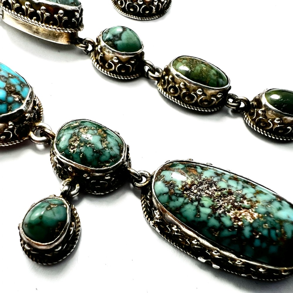 An antique silver jewellery parure consisting of a cabochon turquoise matrix link necklace, drop earrings, and a statement ring. View X