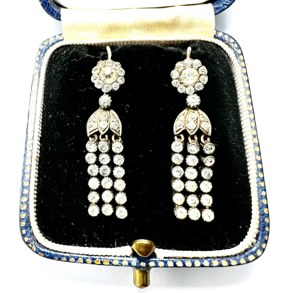 A pair of Victorian silver and gold drop earrings featuring floral cluster tops and articulated paste tassel strands set with clear stones.