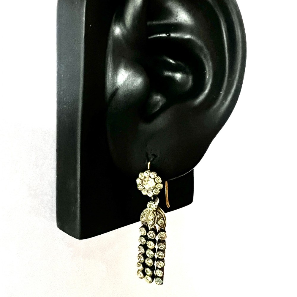A pair of Victorian silver and gold drop earrings featuring floral cluster tops and articulated paste tassel strands set with clear stones. View X