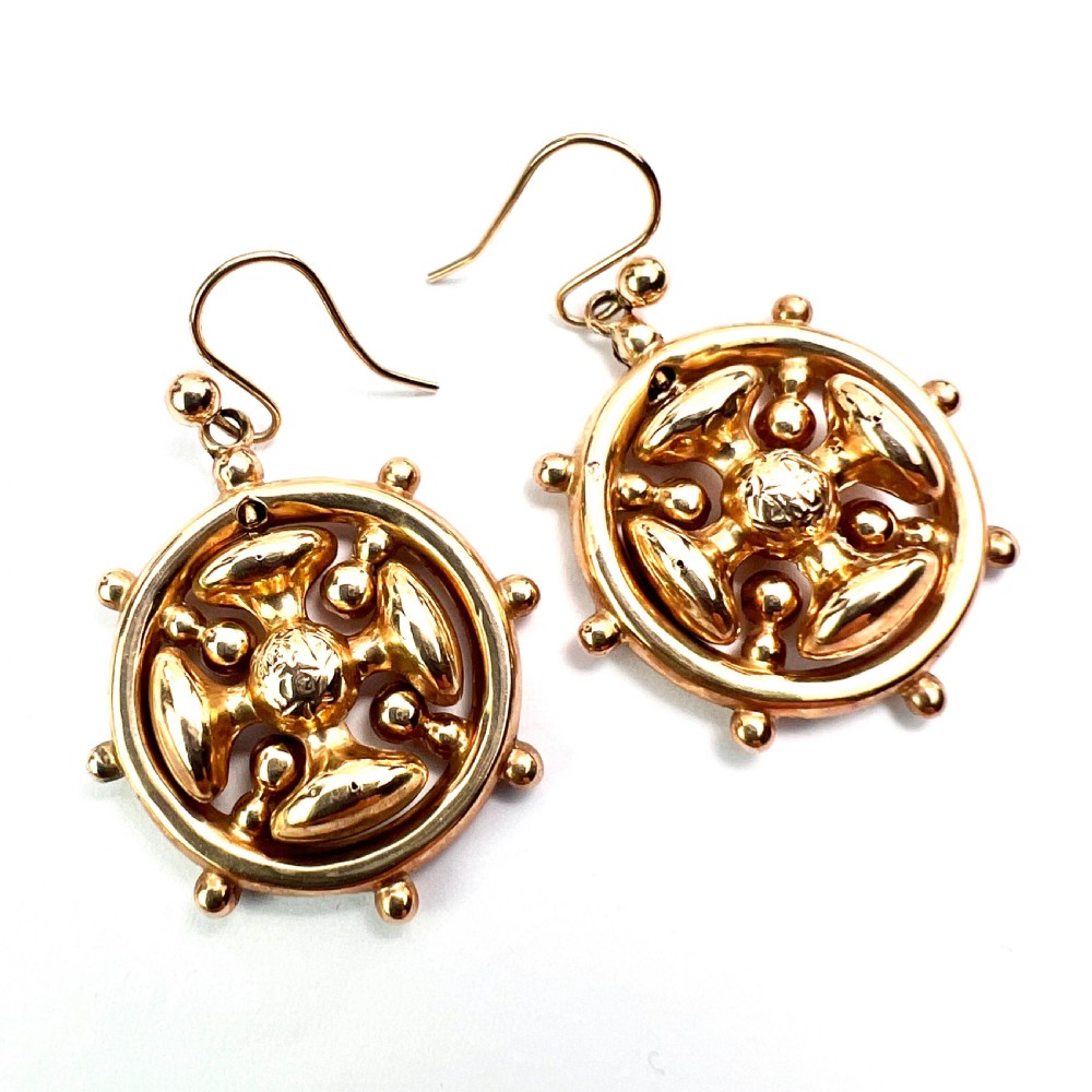 A pair of Victorian 9ct yellow gold drop earrings featuring a circular wheel design with a central square cross motif. View III