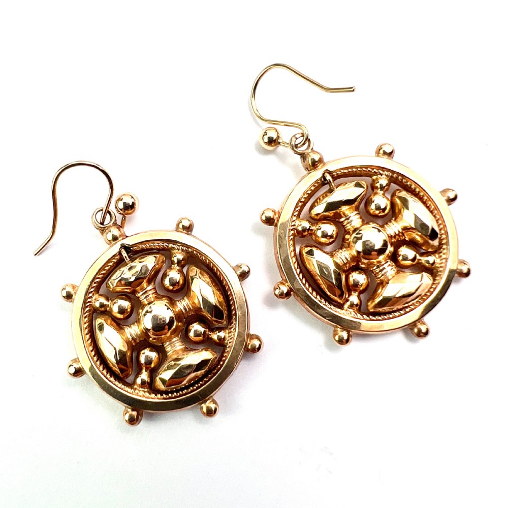 A pair of Victorian 9ct yellow gold drop earrings featuring a circular wheel design with a central square cross motif. View V