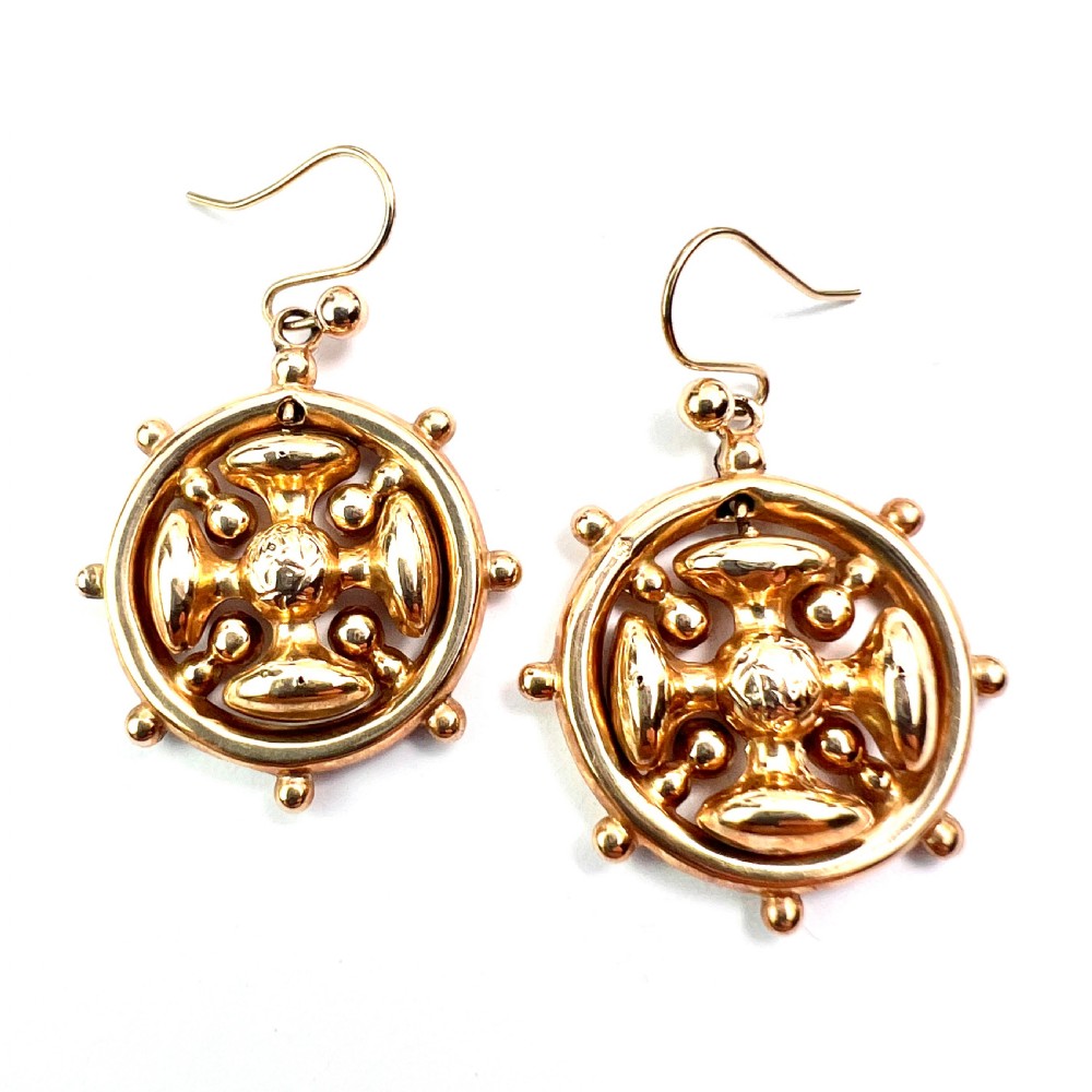 A pair of Victorian 9ct yellow gold drop earrings featuring a circular wheel design with a central square cross motif. View VI