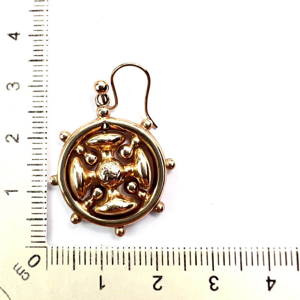 A pair of Victorian 9ct yellow gold drop earrings featuring a circular wheel design with a central square cross motif. View VII