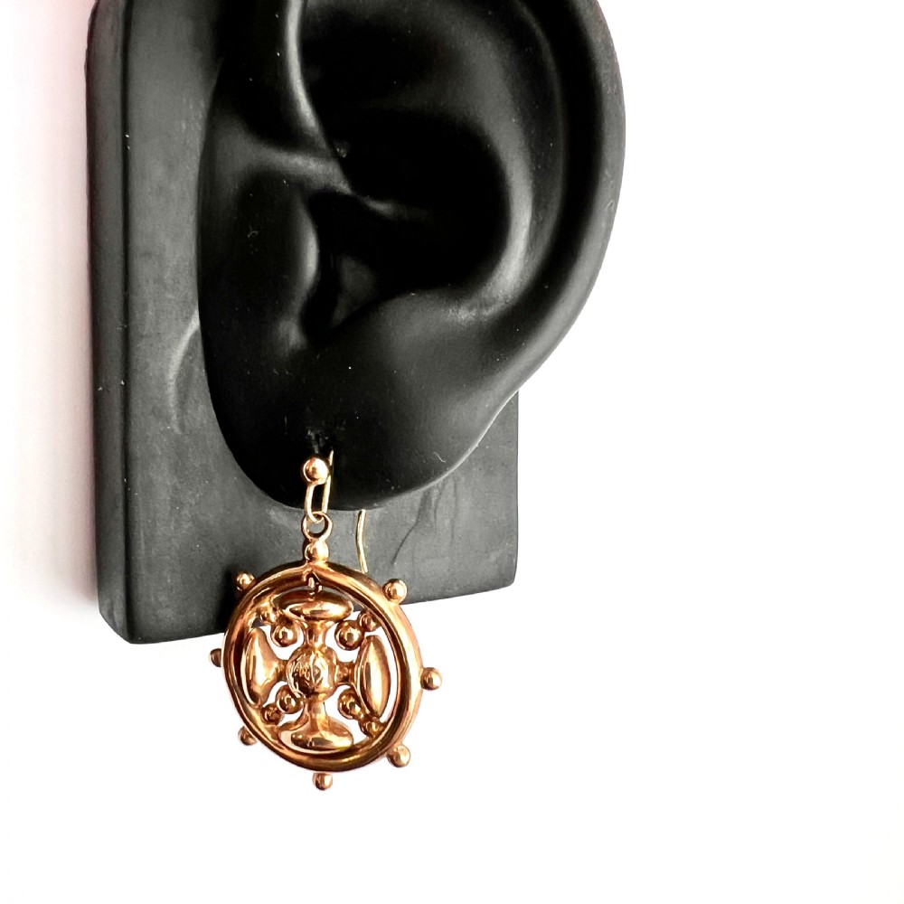 A pair of Victorian 9ct yellow gold drop earrings featuring a circular wheel design with a central square cross motif. View VIII
