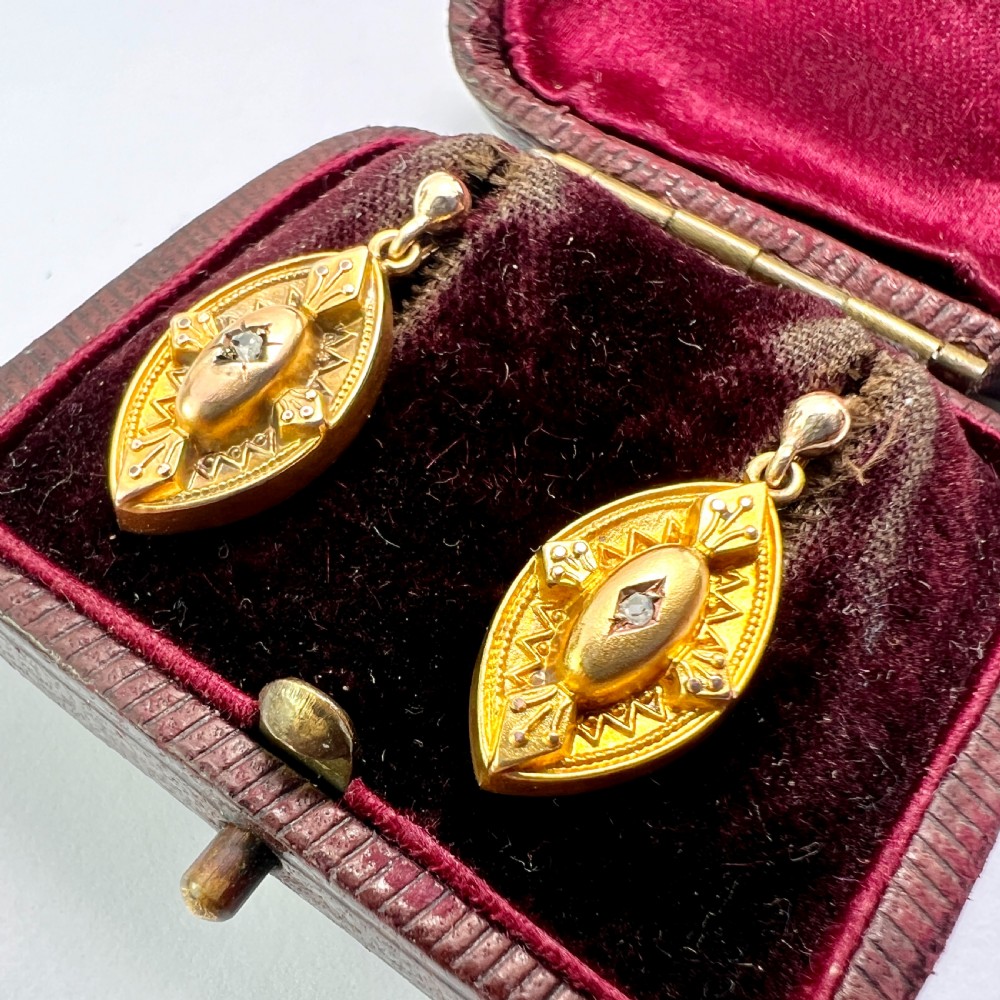 A pair of Victorian 9ct yellow gold marquise-shaped drop earrings featuring star-set diamond centres and engraved geometric detail.