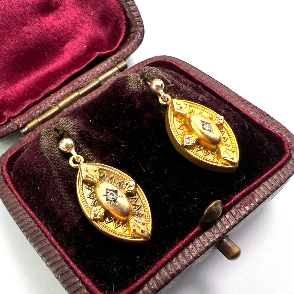 A pair of Victorian 9ct yellow gold marquise-shaped drop earrings featuring star-set diamond centres and engraved geometric detail. View V