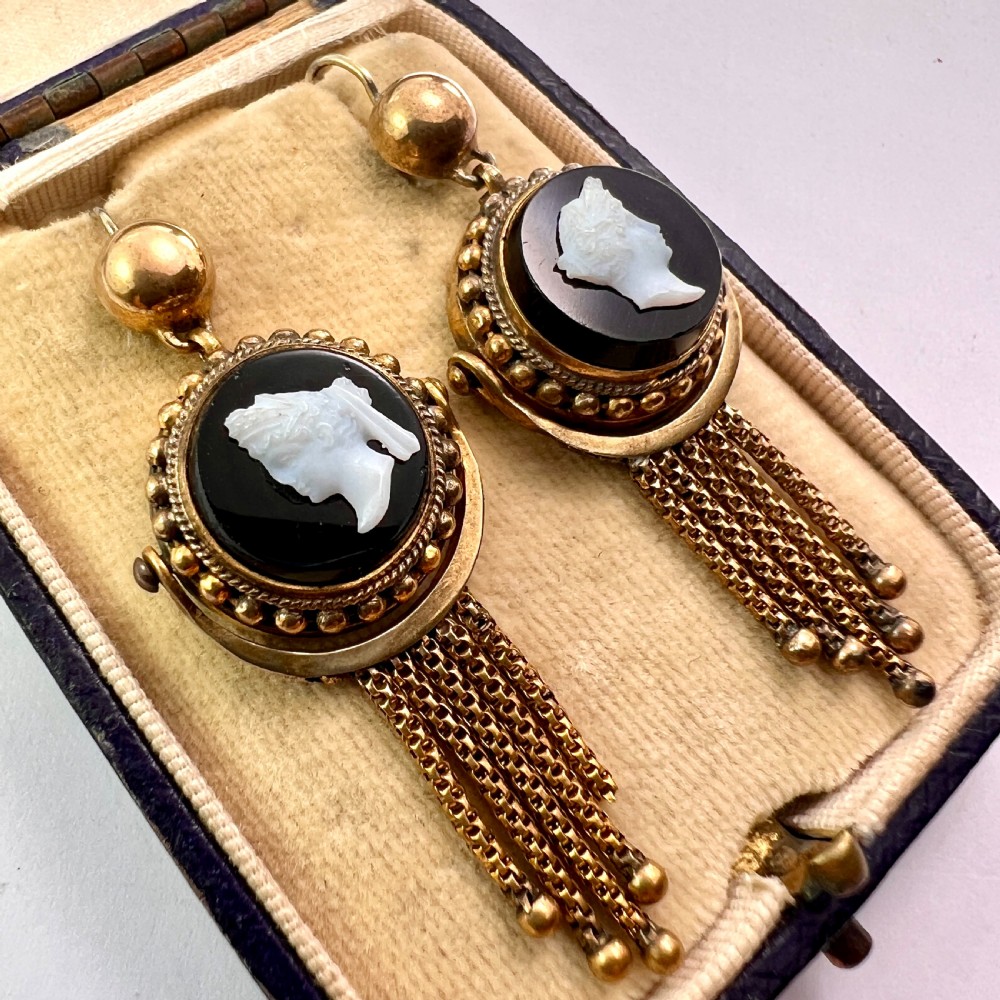 A pair of Victorian gold drop earrings featuring carved classical profile cameos mounted on black discs with cascading foxtail chain tassels. View II