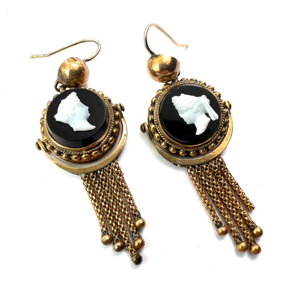 A pair of Victorian gold drop earrings featuring carved classical profile cameos mounted on black discs with cascading foxtail chain tassels. View V