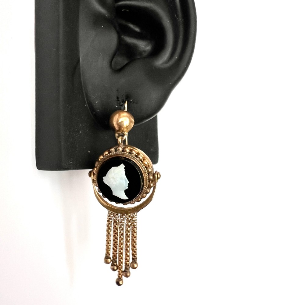 A pair of Victorian gold drop earrings featuring carved classical profile cameos mounted on black discs with cascading foxtail chain tassels. View X
