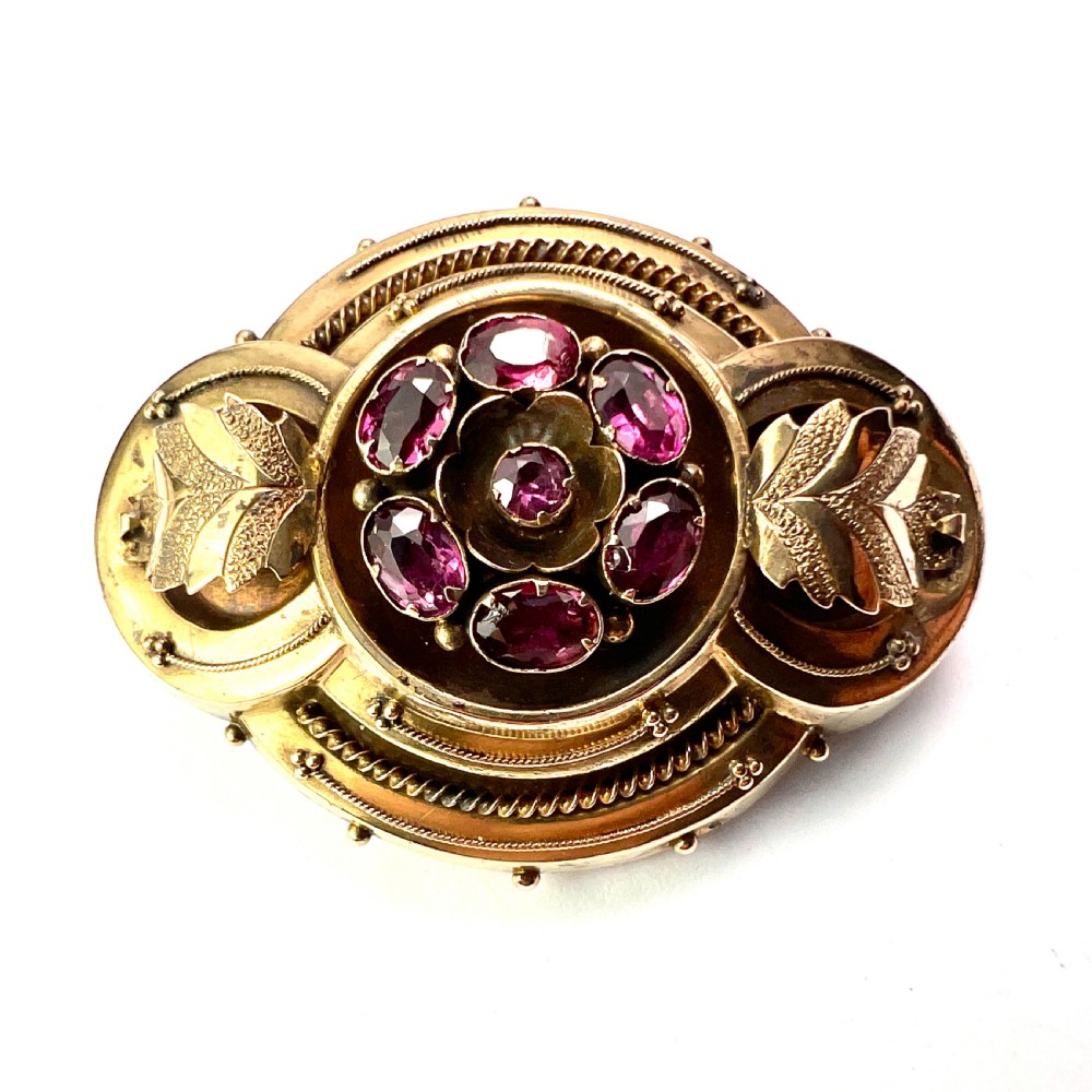 A Victorian gold demi parure set featuring an ornate oval brooch and matching drop earrings inset with amethysts, presented inside a blue velvet-lined case. View III
