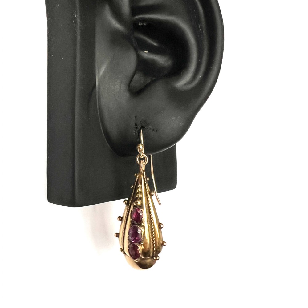 A Victorian gold demi parure set featuring an ornate oval brooch and matching drop earrings inset with amethysts, presented inside a blue velvet-lined case. View VIII