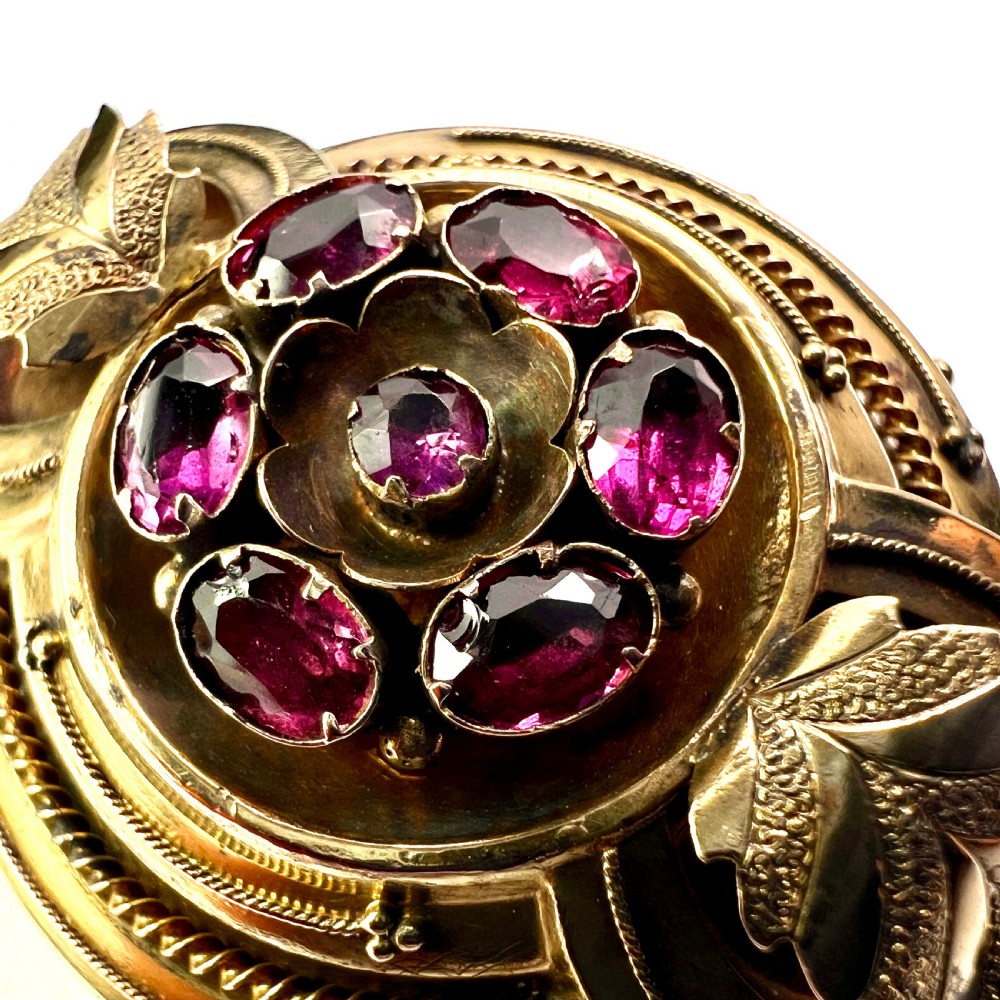 A Victorian gold demi parure set featuring an ornate oval brooch and matching drop earrings inset with amethysts, presented inside a blue velvet-lined case. View XI