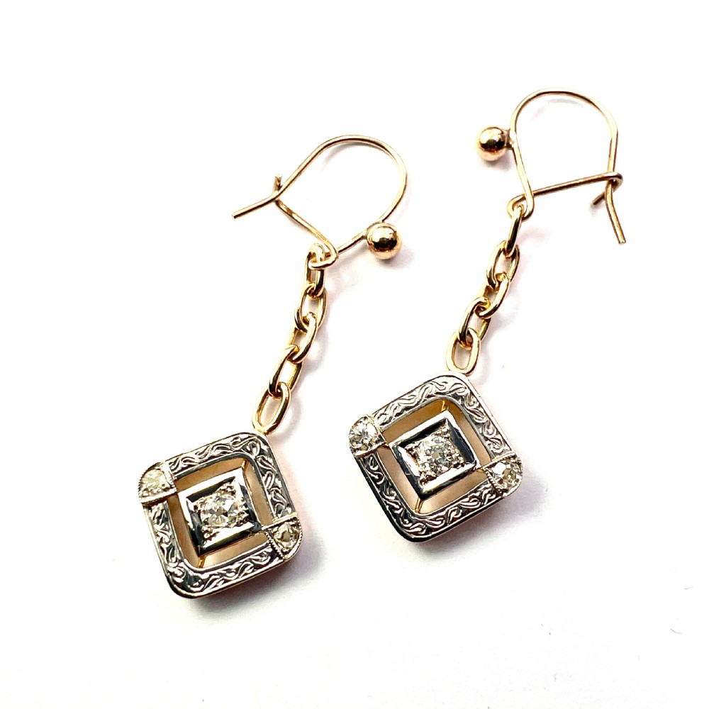 A pair of Edwardian style diamond drop earrings crafted in yellow and white gold with diamond-shaped engraved pendants. View V