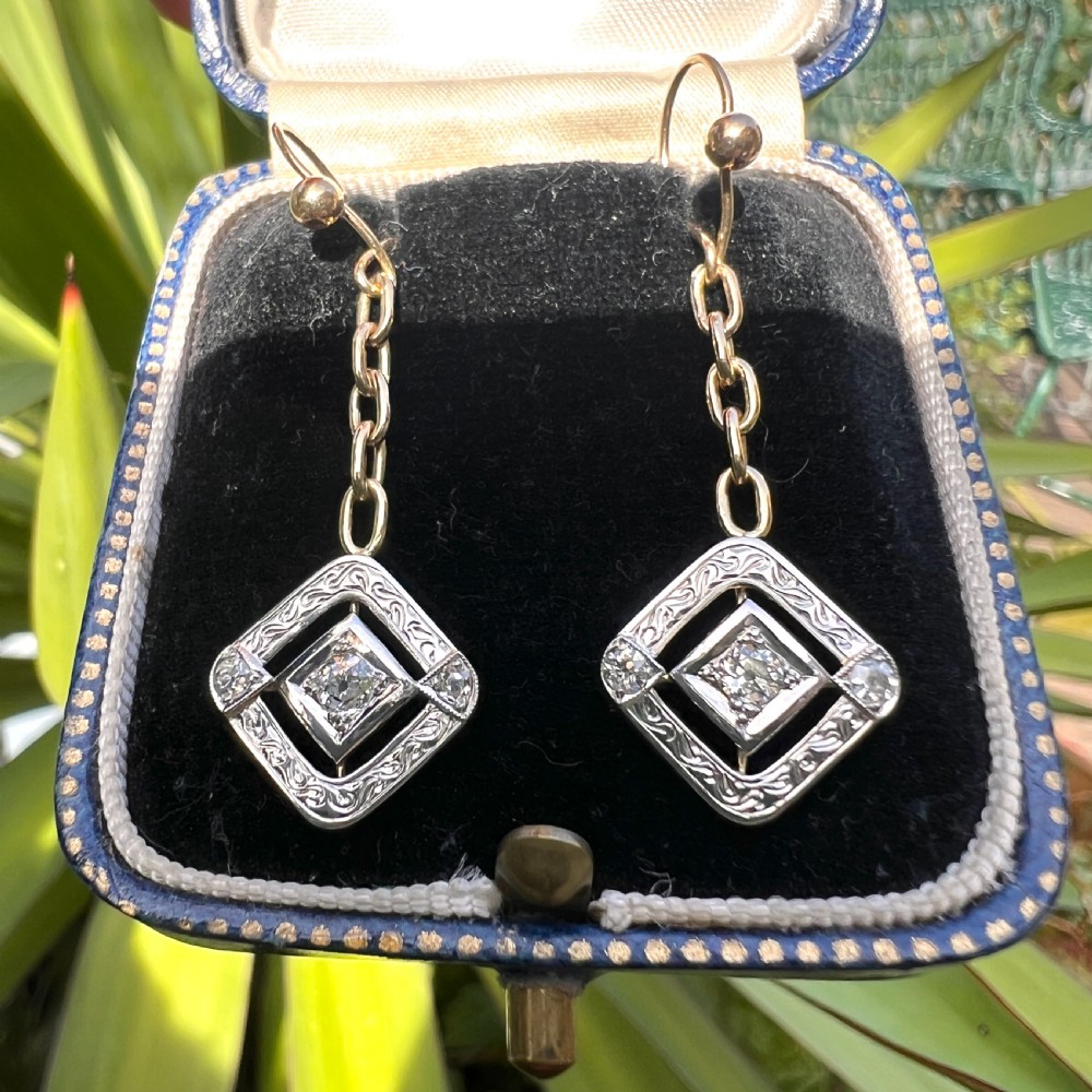 A pair of Edwardian style diamond drop earrings crafted in yellow and white gold with diamond-shaped engraved pendants. View IX