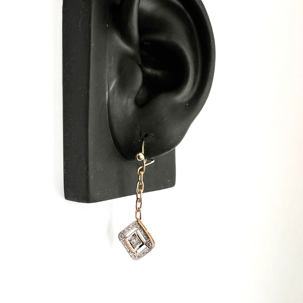 A pair of Edwardian style diamond drop earrings crafted in yellow and white gold with diamond-shaped engraved pendants. View X