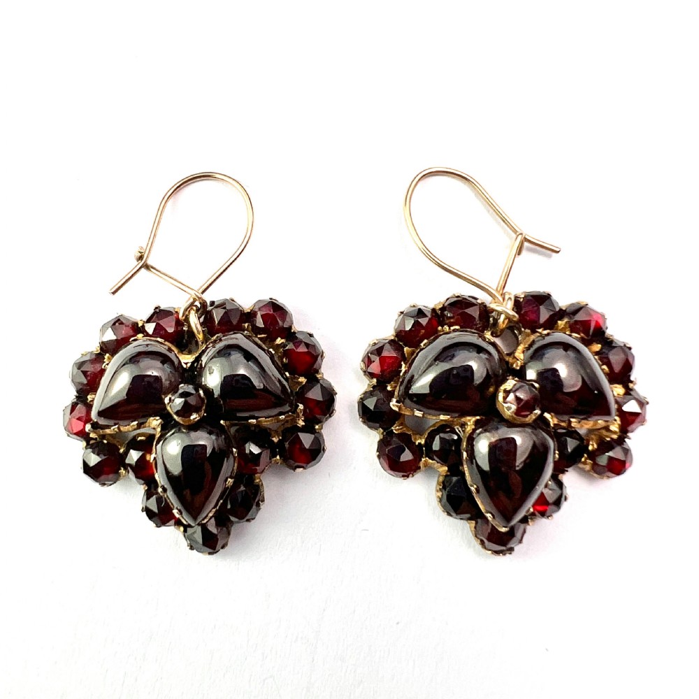 A pair of Victorian Bohemian garnet cluster drop earrings featuring cabochon central garnets surrounded by rose-cut pyrope garnets set on gold wire hooks. View II