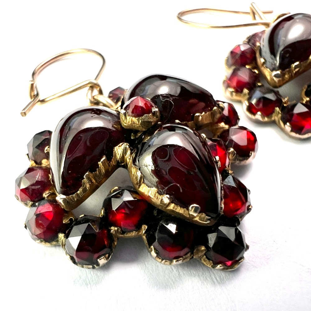 A pair of Victorian Bohemian garnet cluster drop earrings featuring cabochon central garnets surrounded by rose-cut pyrope garnets set on gold wire hooks. View III