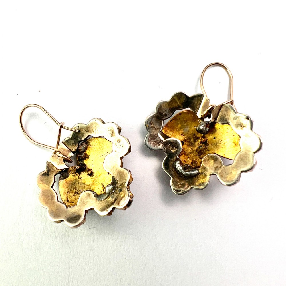 A pair of Victorian Bohemian garnet cluster drop earrings featuring cabochon central garnets surrounded by rose-cut pyrope garnets set on gold wire hooks. View V
