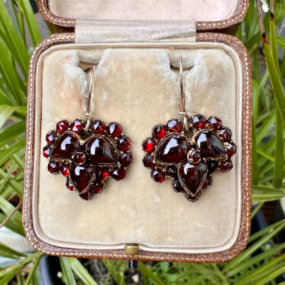 A pair of Victorian Bohemian garnet cluster drop earrings featuring cabochon central garnets surrounded by rose-cut pyrope garnets set on gold wire hooks. View VII