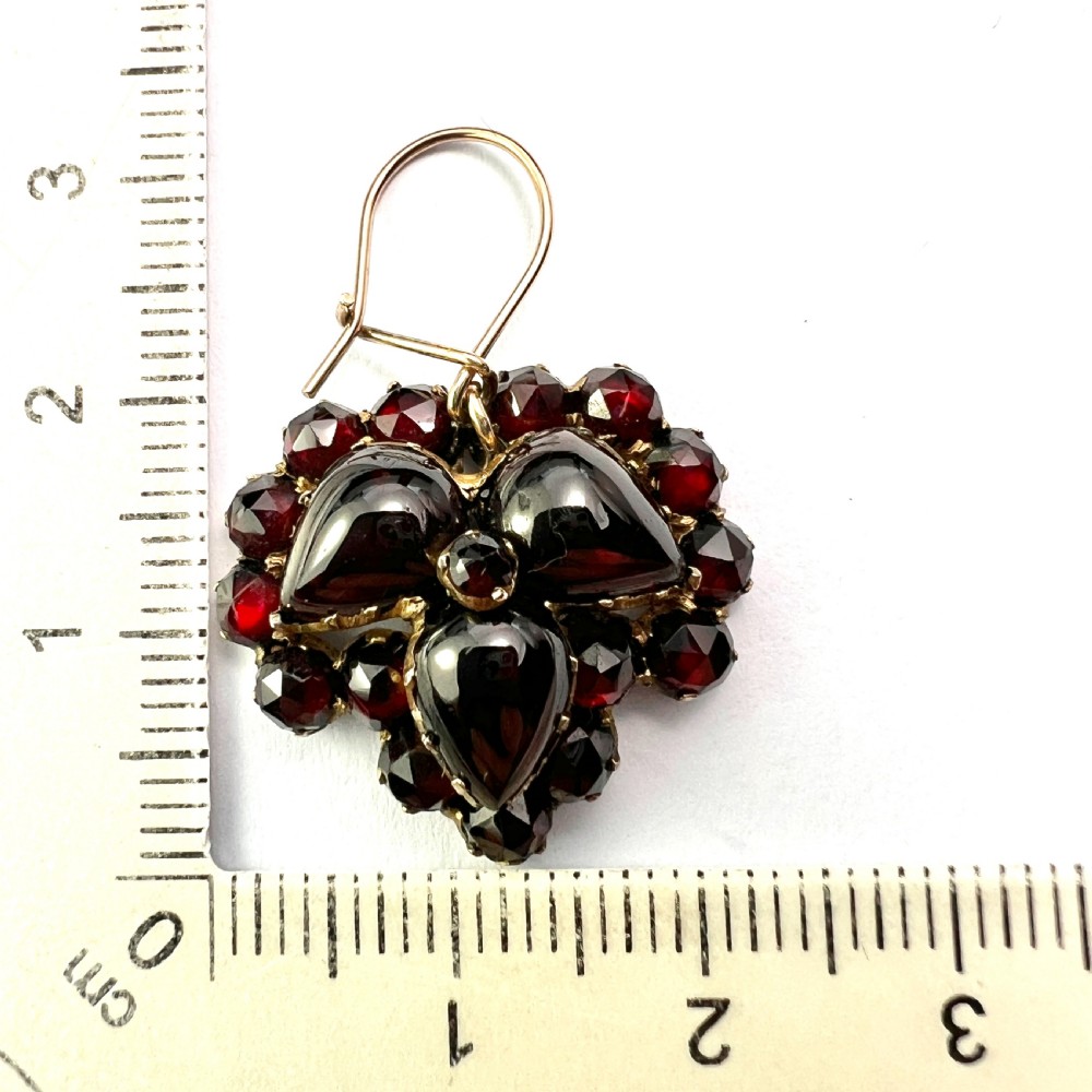 A pair of Victorian Bohemian garnet cluster drop earrings featuring cabochon central garnets surrounded by rose-cut pyrope garnets set on gold wire hooks. View VIII