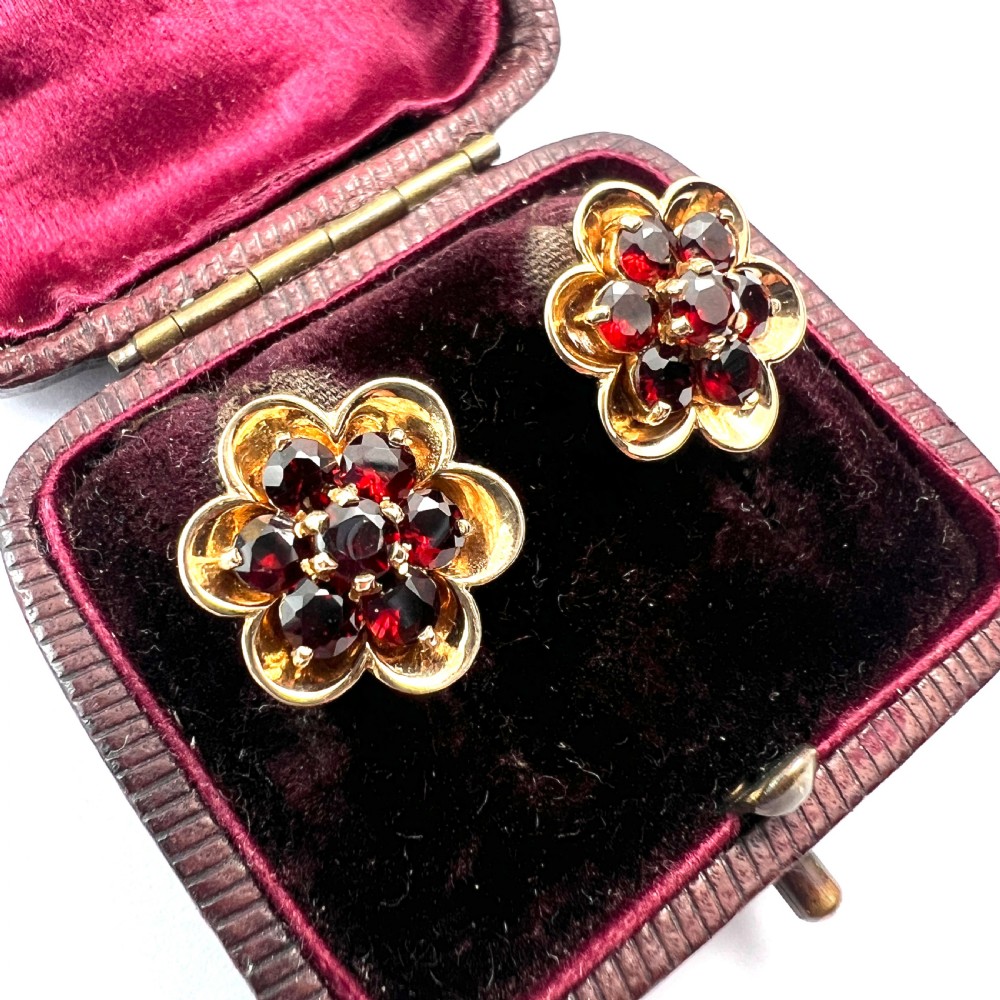 A pair of 9ct yellow gold floral cluster stud earrings set with round deep red garnet gemstones in claw settings. View II