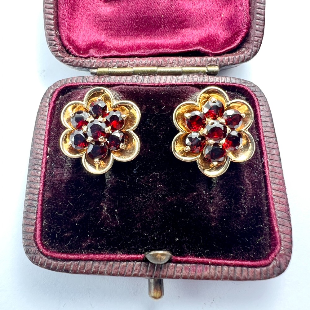 A pair of 9ct yellow gold floral cluster stud earrings set with round deep red garnet gemstones in claw settings. View III