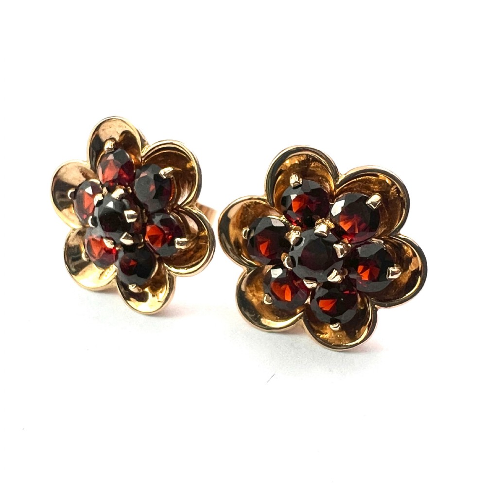 A pair of 9ct yellow gold floral cluster stud earrings set with round deep red garnet gemstones in claw settings. View V