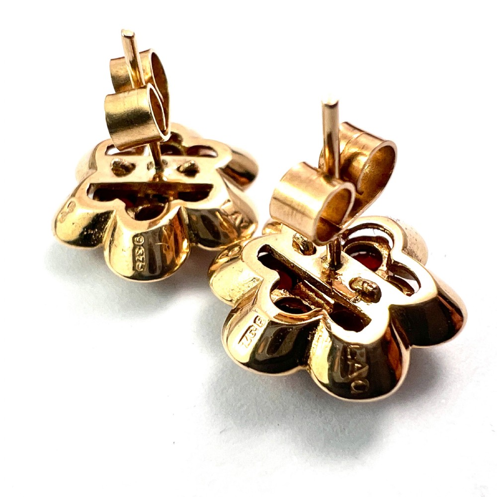 A pair of 9ct yellow gold floral cluster stud earrings set with round deep red garnet gemstones in claw settings. View VII