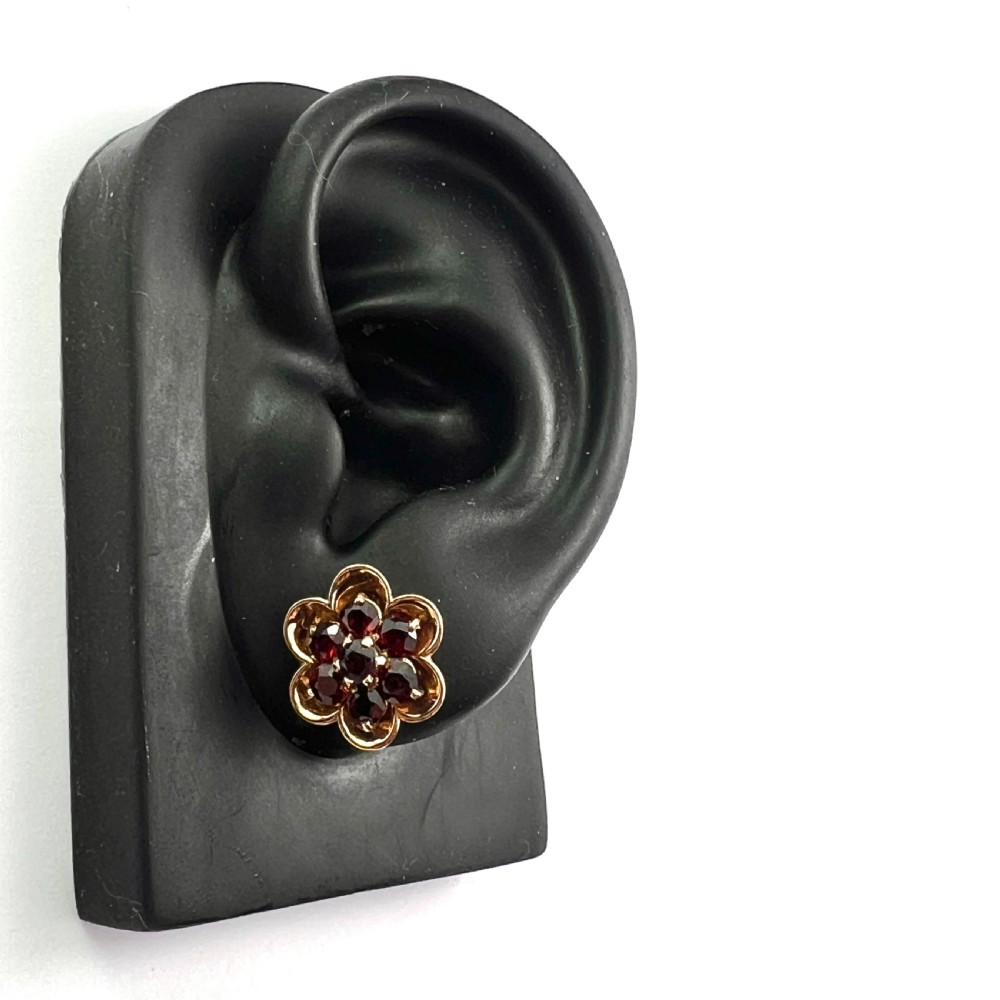 A pair of 9ct yellow gold floral cluster stud earrings set with round deep red garnet gemstones in claw settings. View IX